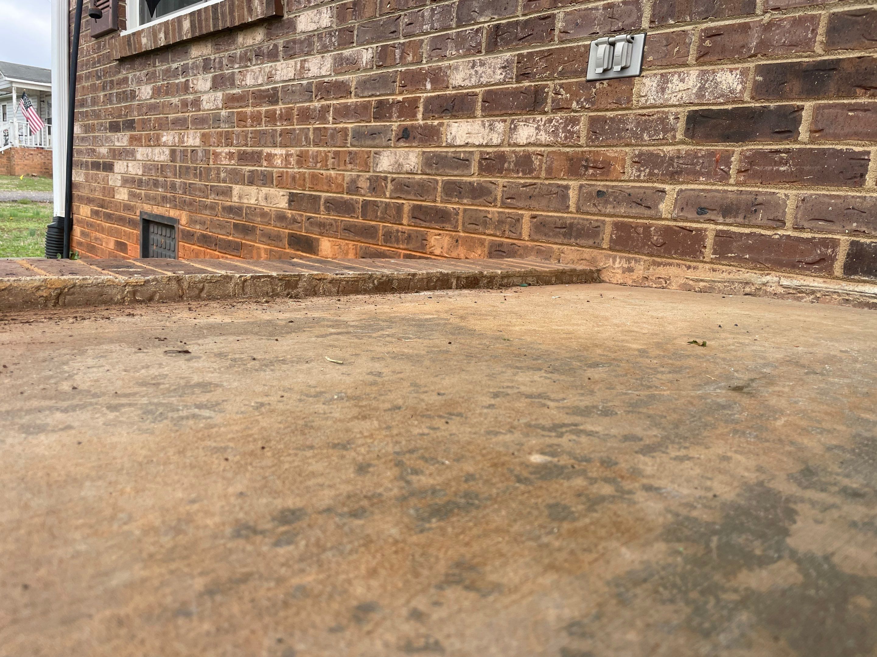 Concrete patio separated from house foundation with visible gap