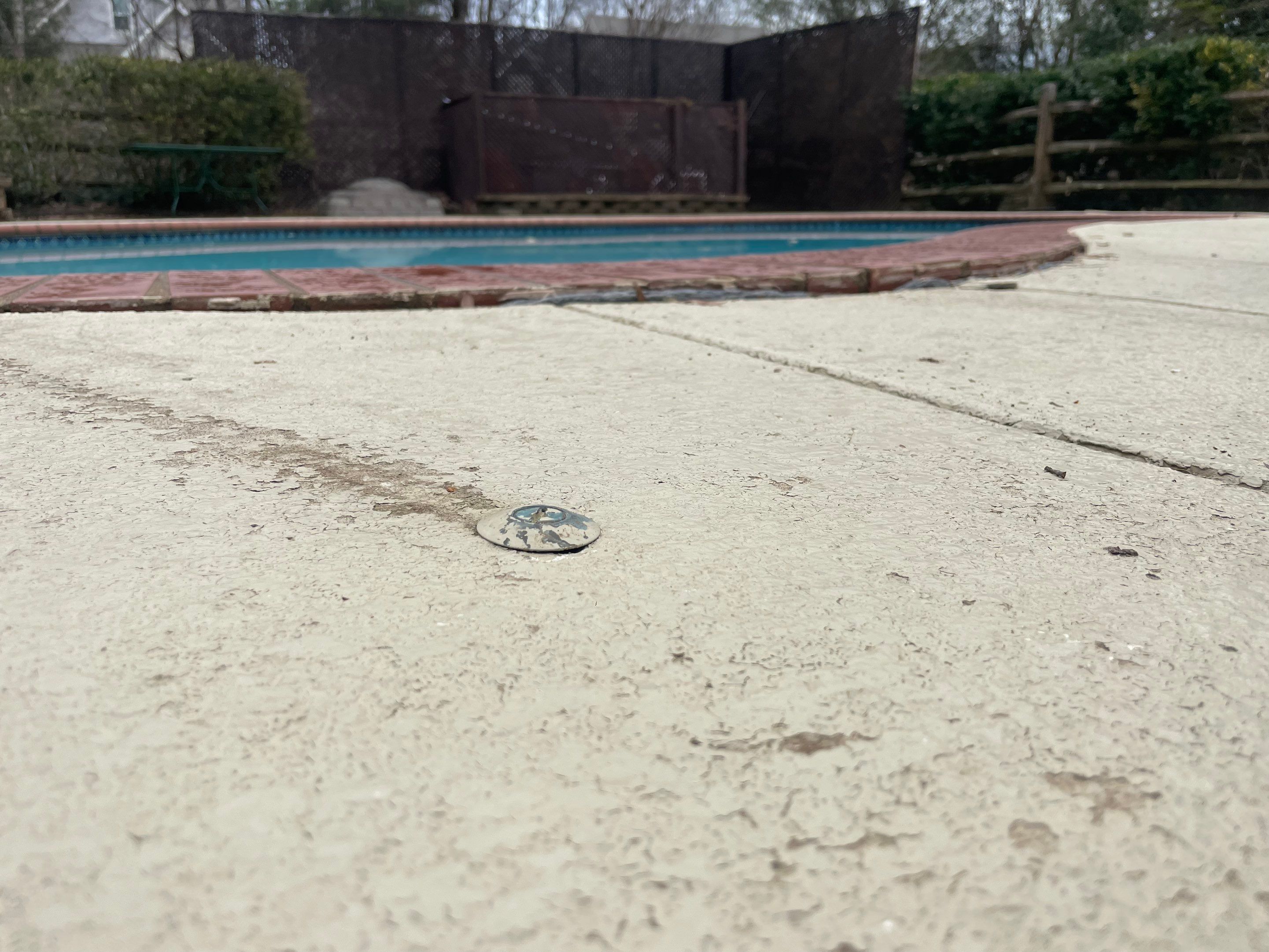 Hairline cracks across a sunken pool deck slab